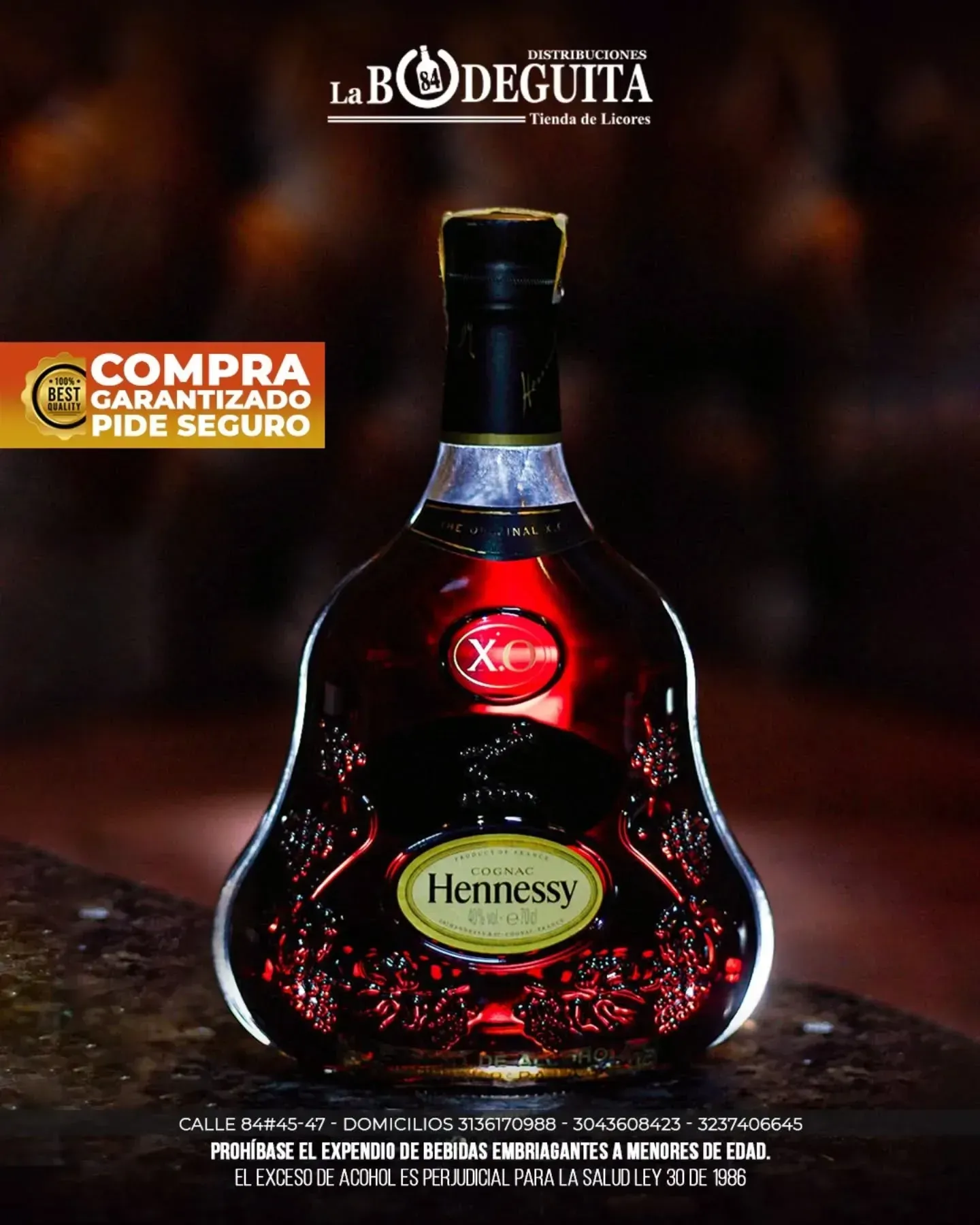 Botella de coñac Hennessy iluminada, con el logo y texto “La Bodeguita” sobre fondo oscuro.