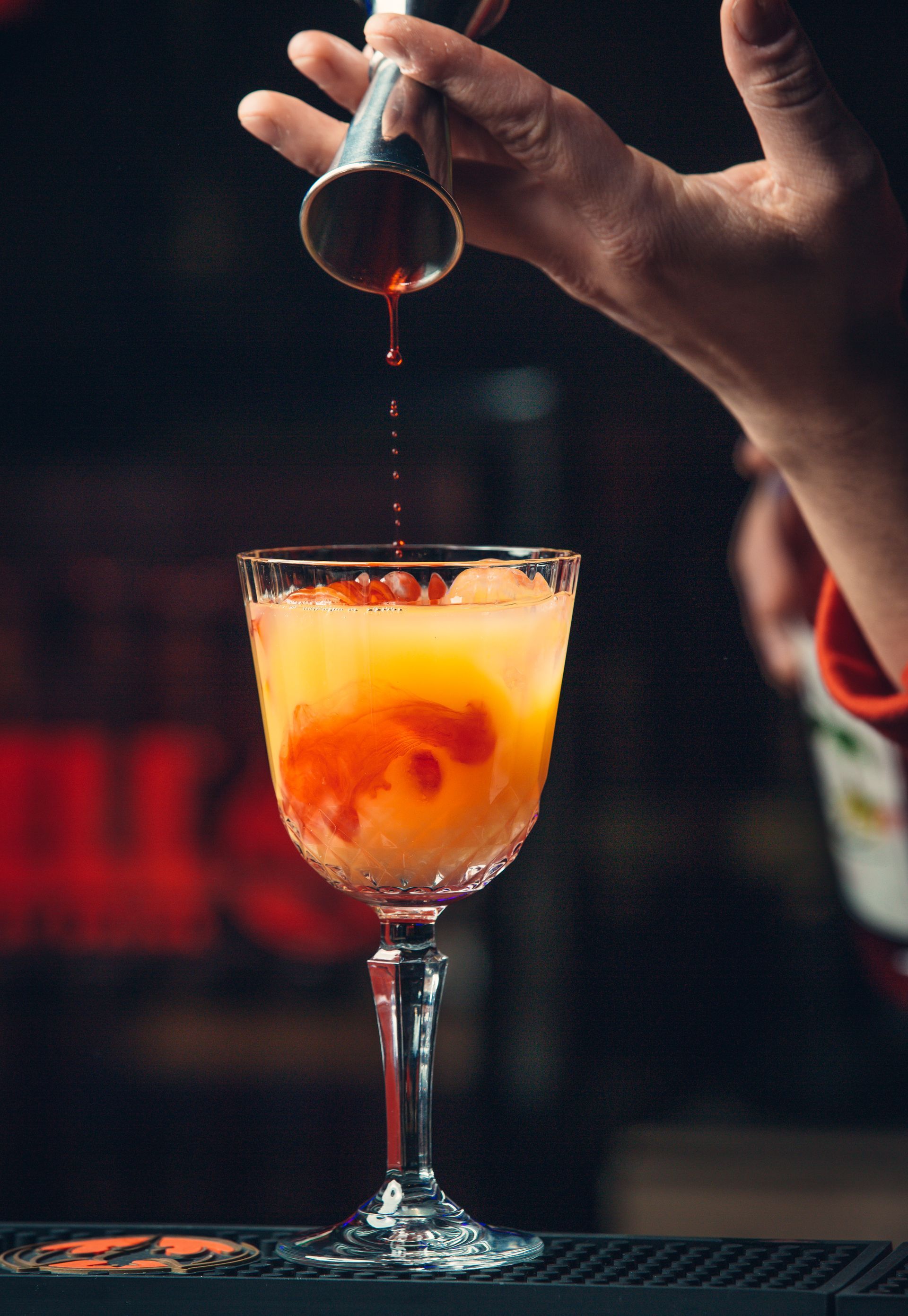 Un barman verse une boisson dans un verre à vin.