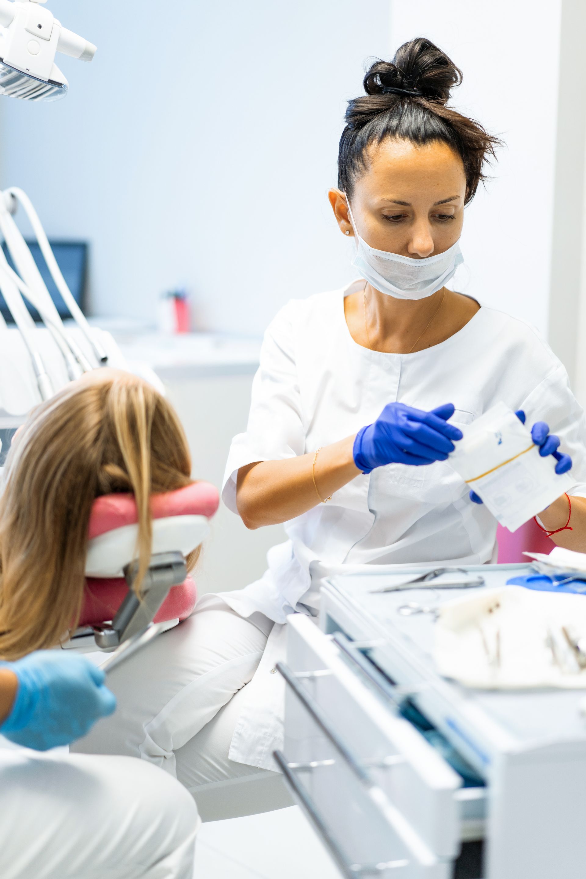 Une dentiste examine les dents d'une jeune fille dans un cabinet dentaire.