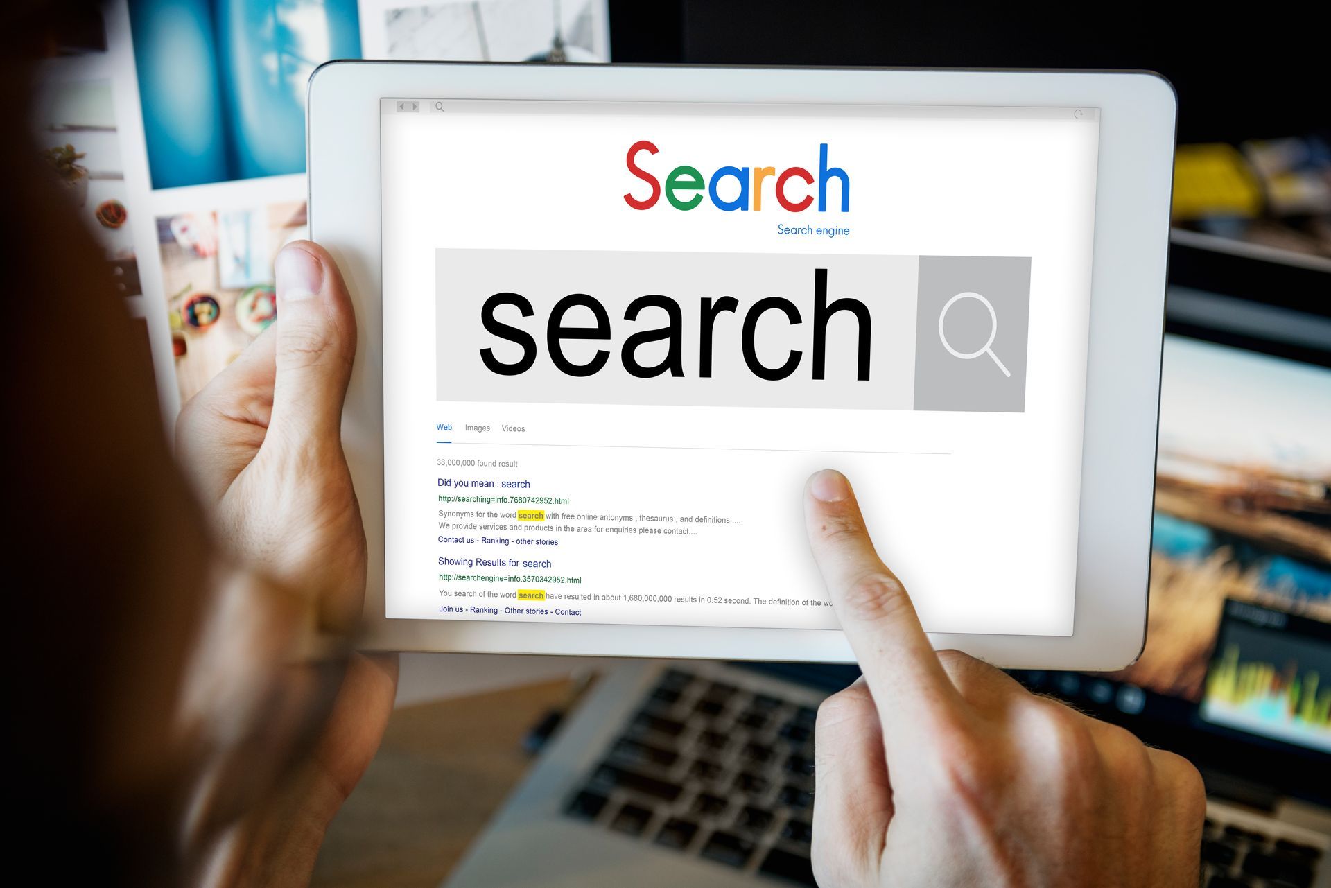 Une personne tient une tablette avec la recherche de mots sur l'écran.