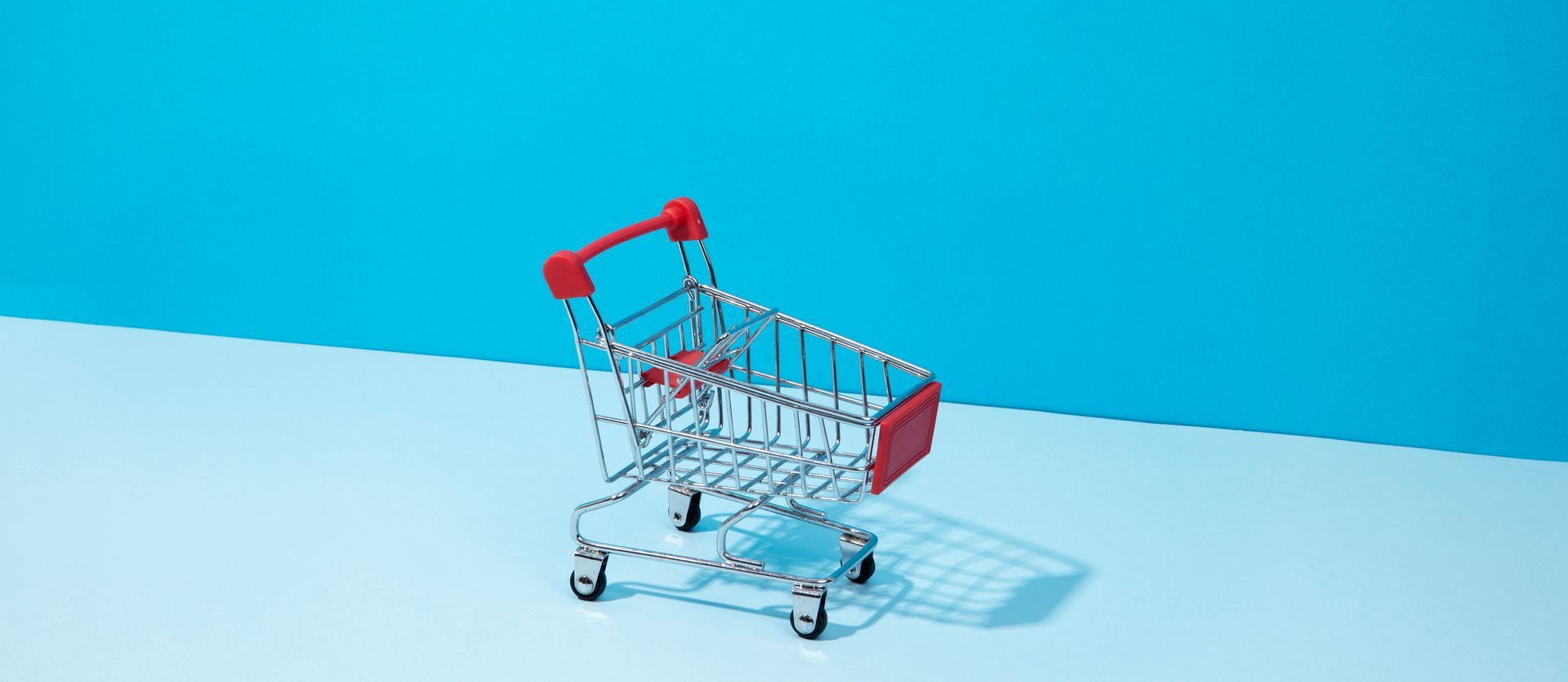 Un petit chariot avec une poignée rouge est posé sur une surface bleue.