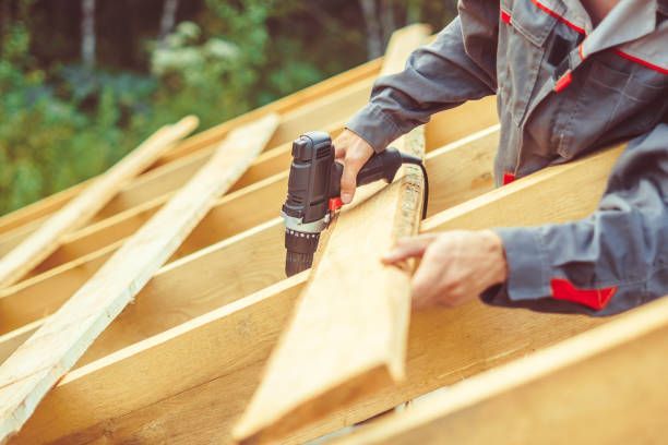 A worker is performing deck installation, securing wooden planks to create a durable structure.