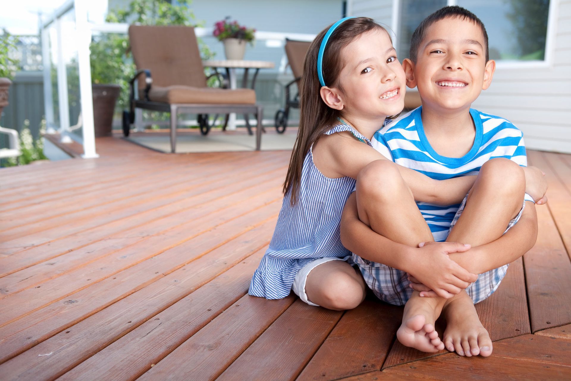 Two siblings, a boy and a girl, sitting on the front deck of their home. Two siblings, a boy and a girl, sitting on the front deck of their home.