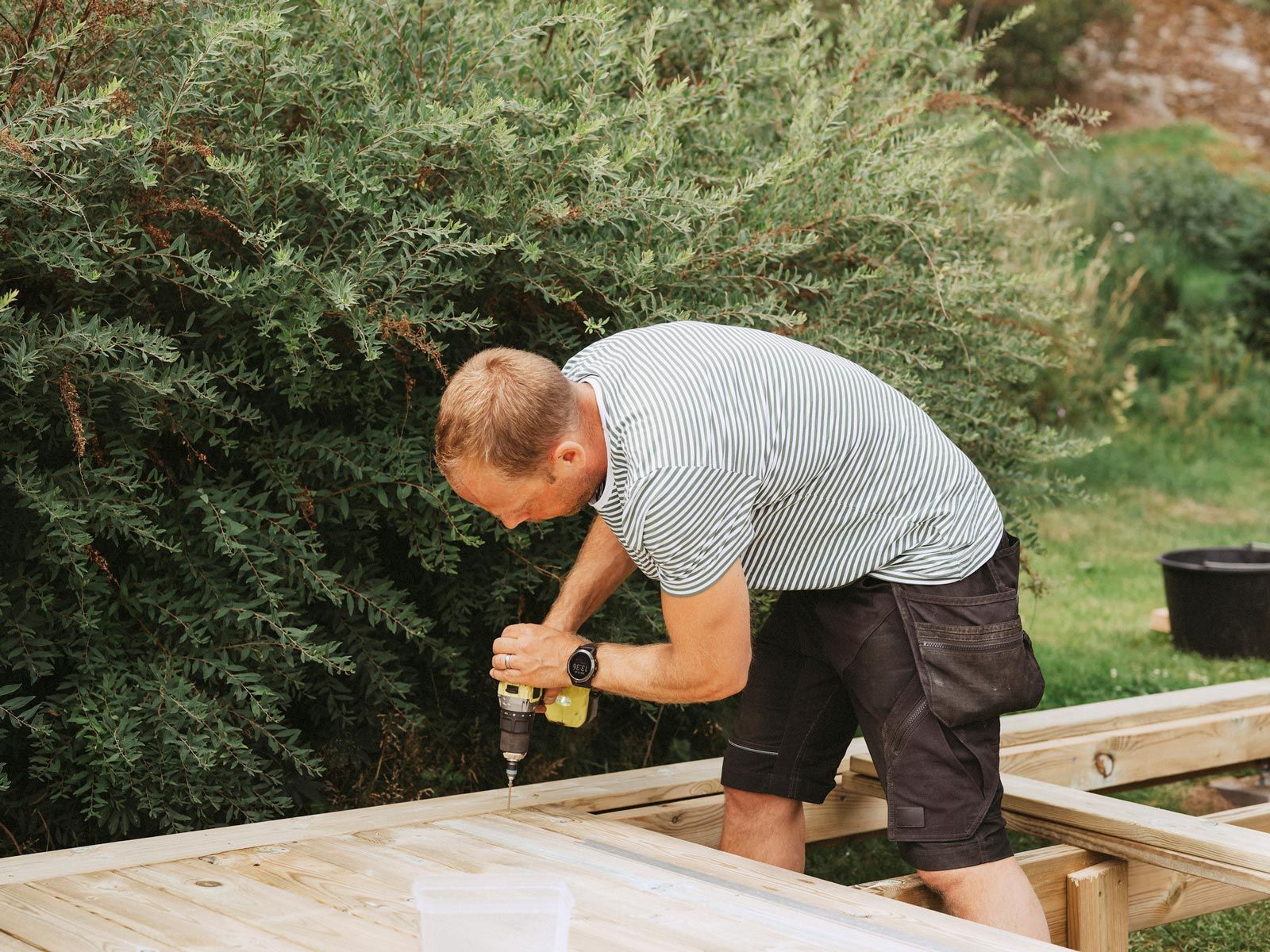 Man building a wooden deck outdoors for home improvement. Man building a wooden deck outdoors for home improvement.