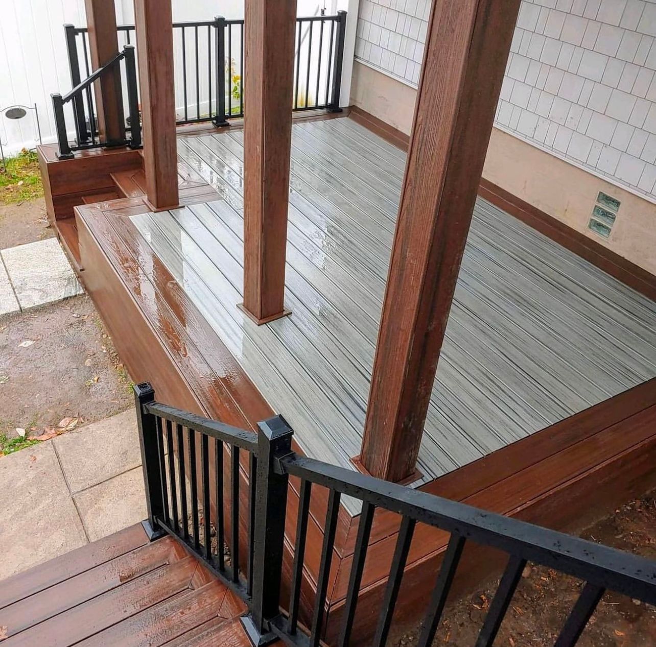 Newly built wooden deck with brown and gray composite boards; black railings.
