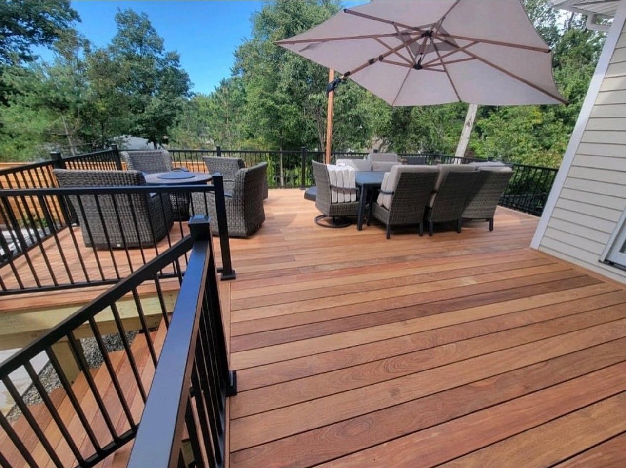 A spacious wooden deck with patio furniture, a large umbrella, and a railing.