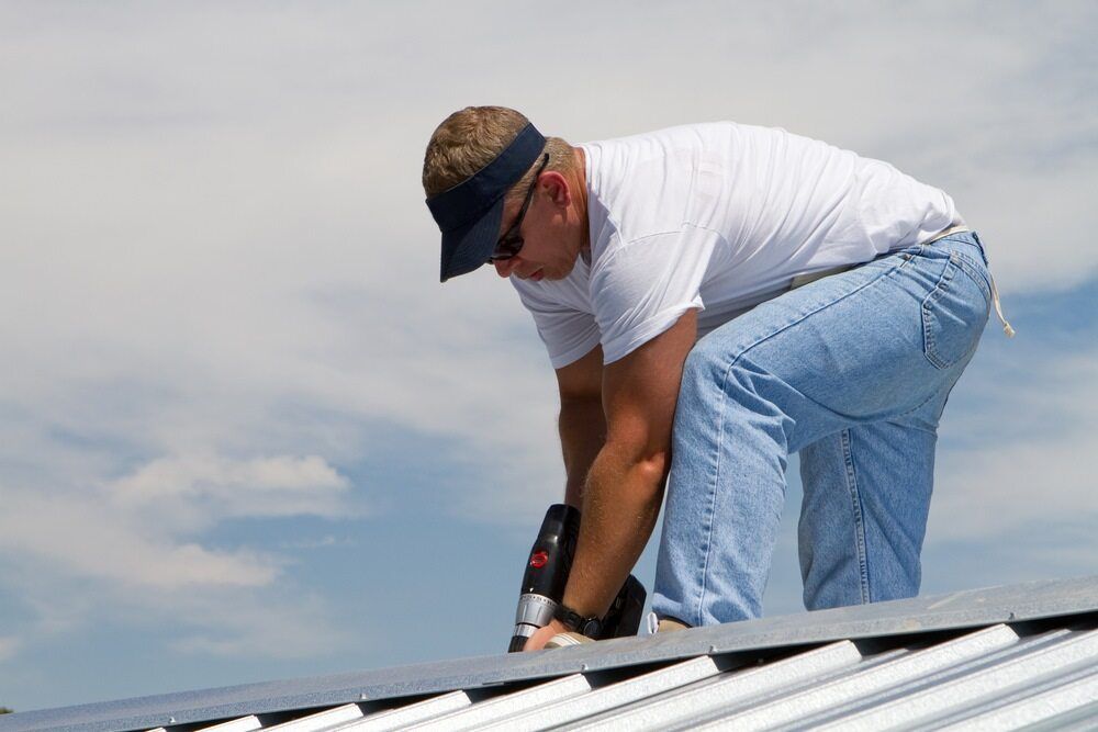 A Man Is Working on A Roof with A Drill — A & B Lattice World & Patios in Northern Beaches, QLD