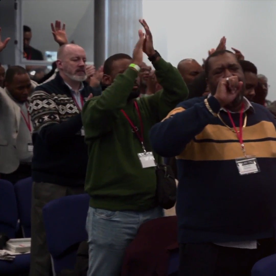People with raised hands and clapping in a conference hall.