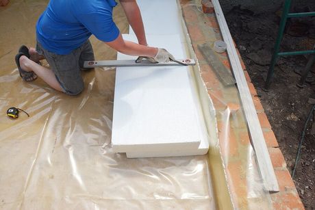 a man in a blue shirt is working on a wall