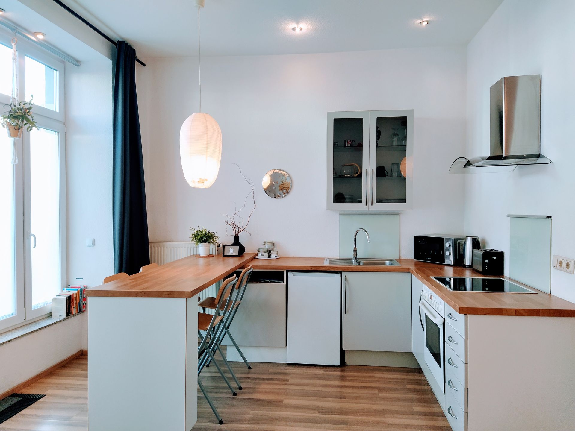 A kitchen with white cabinets and a wooden counter top in our Berlin vacation apartment.