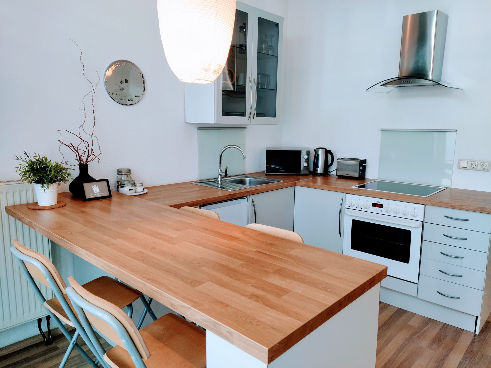 A kitchen with a wooden counter top and white cabinets in our Berlin vacation rental