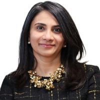 Woman with dark hair, wearing a gold necklace, smiles slightly; head and shoulders shot.