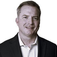 Man in suit jacket smiles at the camera against a white background.
