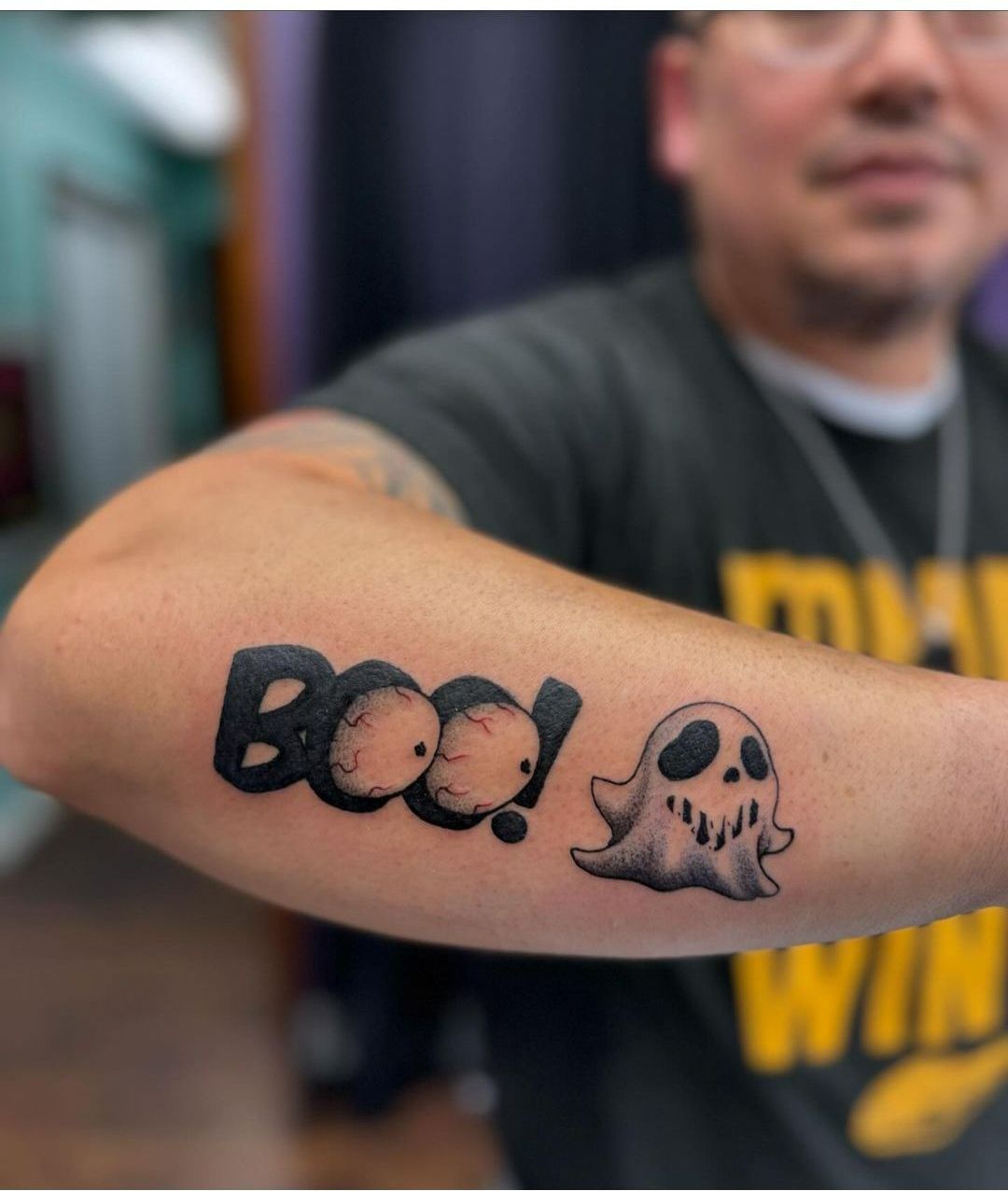 A man has a tattoo on his arm that says boo !