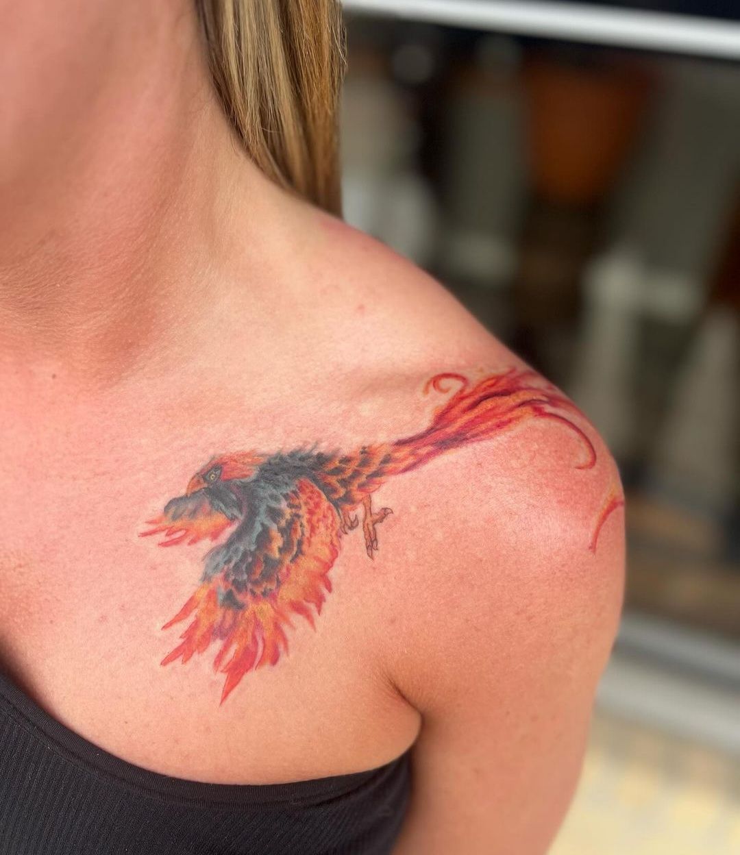 A woman has a phoenix tattoo on her shoulder.