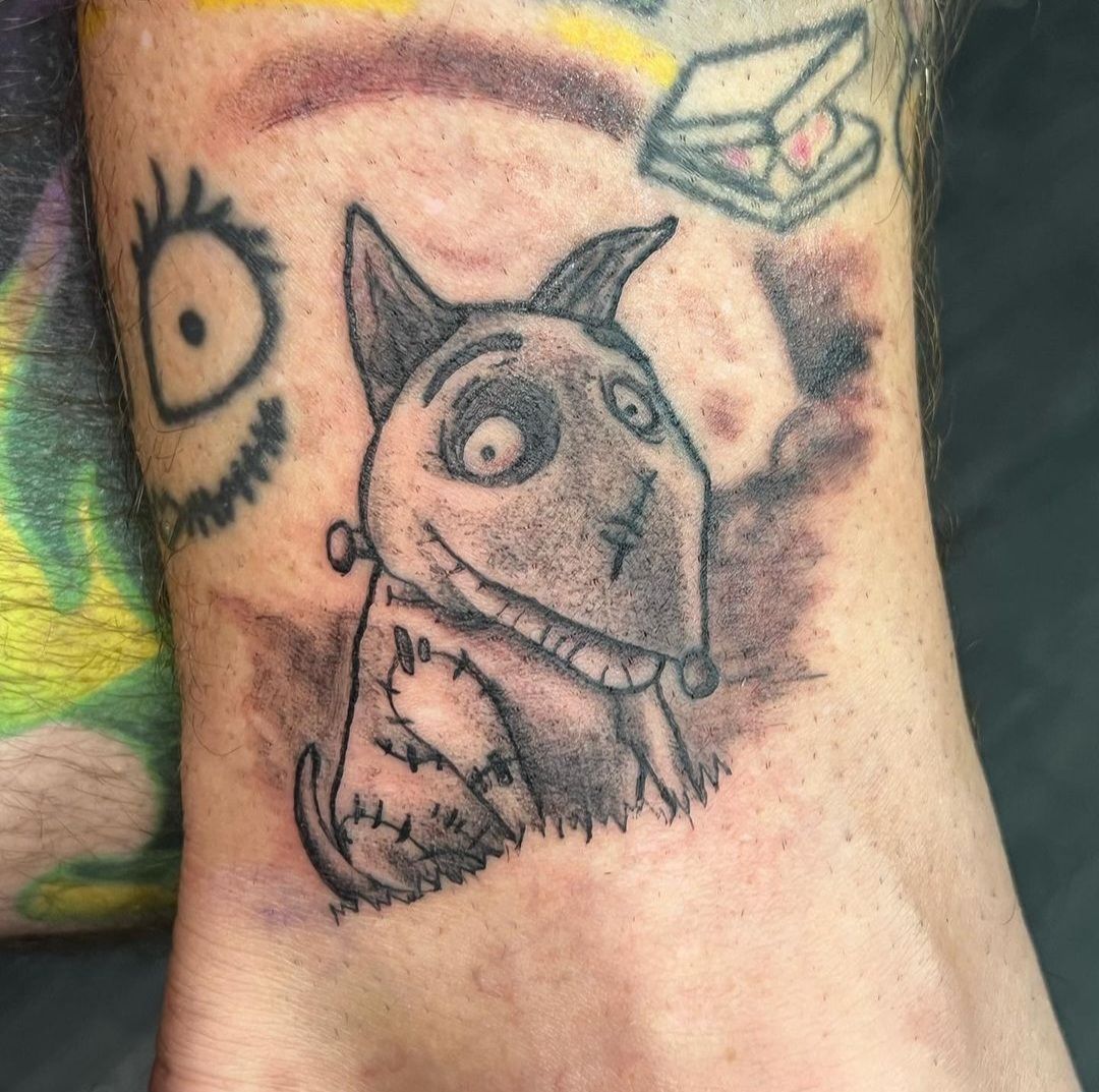 A person has a tattoo of a dog on their ankle.