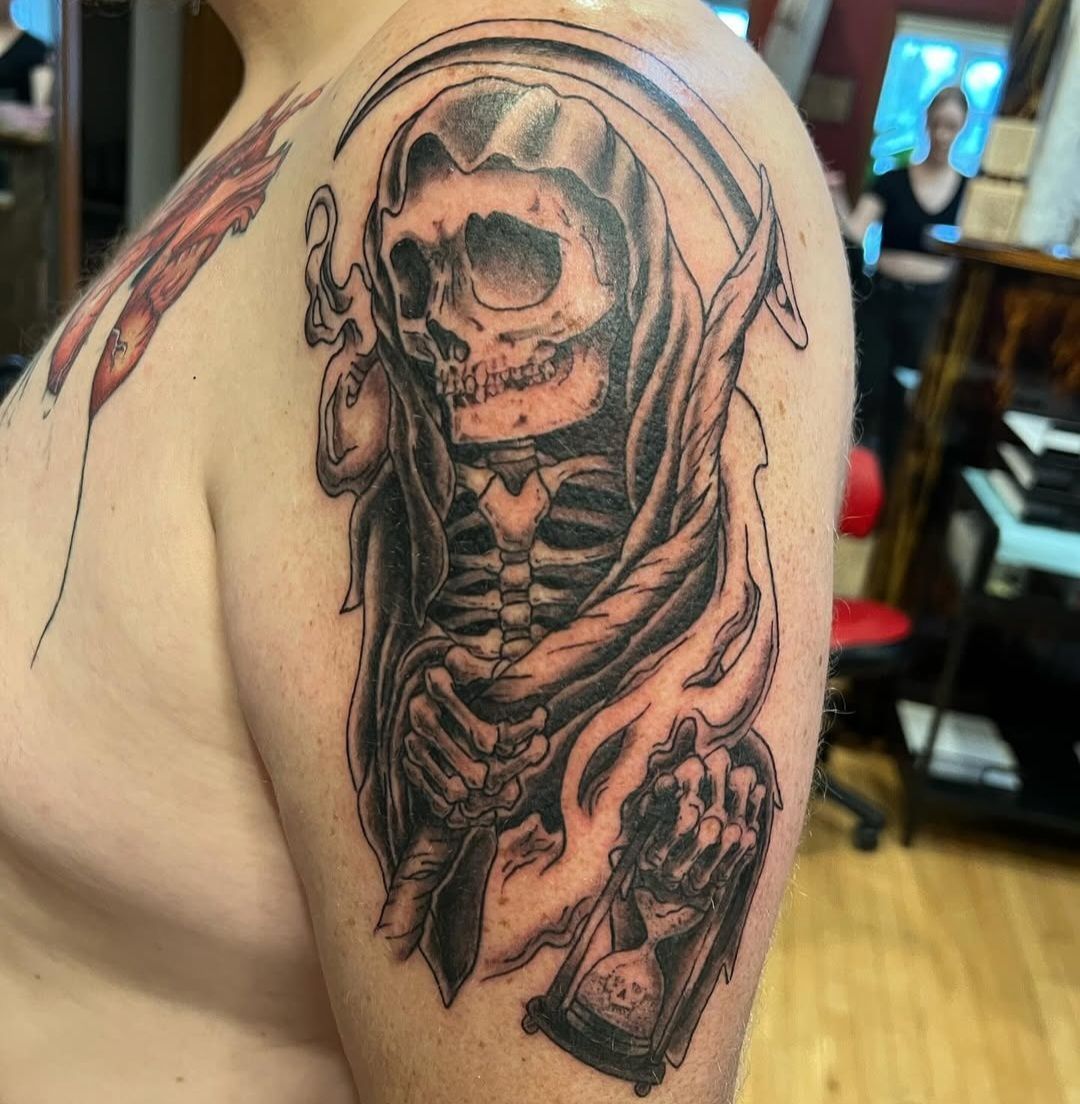 A man has a grim reaper tattoo on his arm