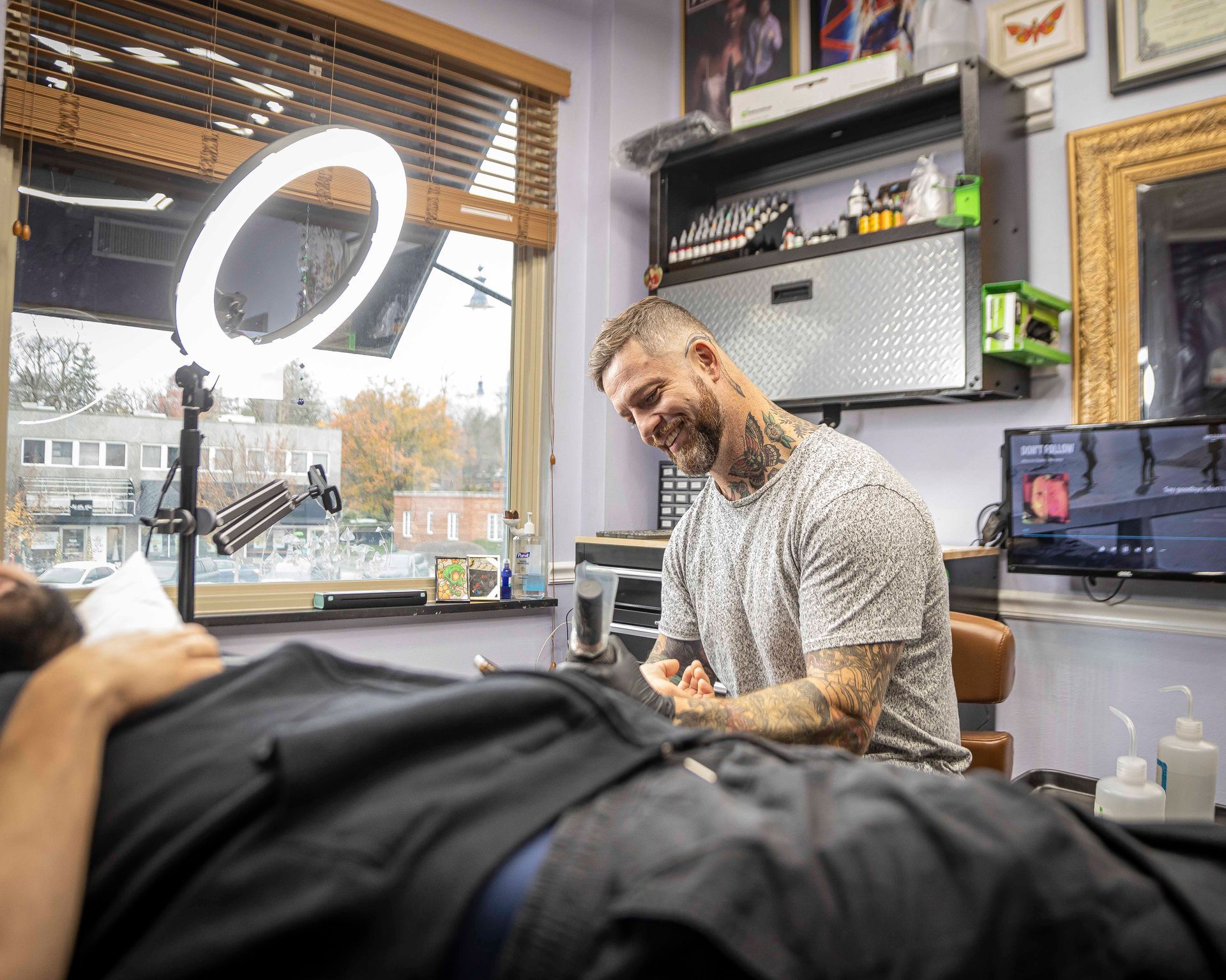 A man with a beard and tattoos is sitting in a chair.