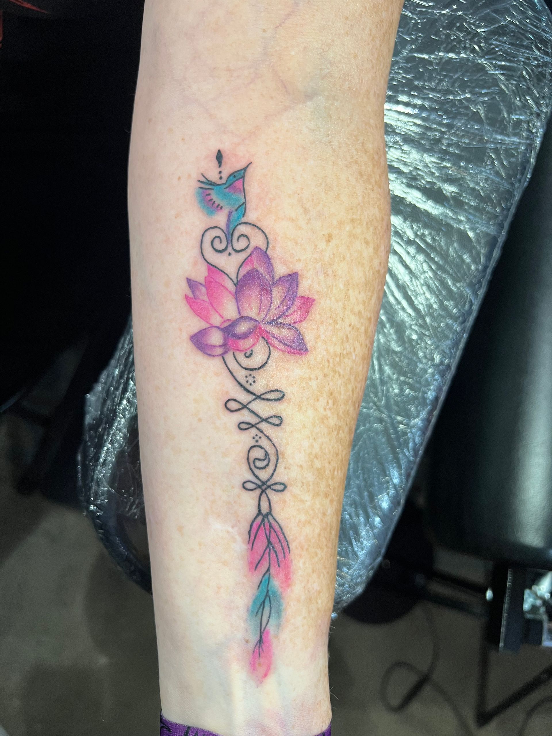 A man is getting a tattoo on another man 's chest in a tattoo shop.