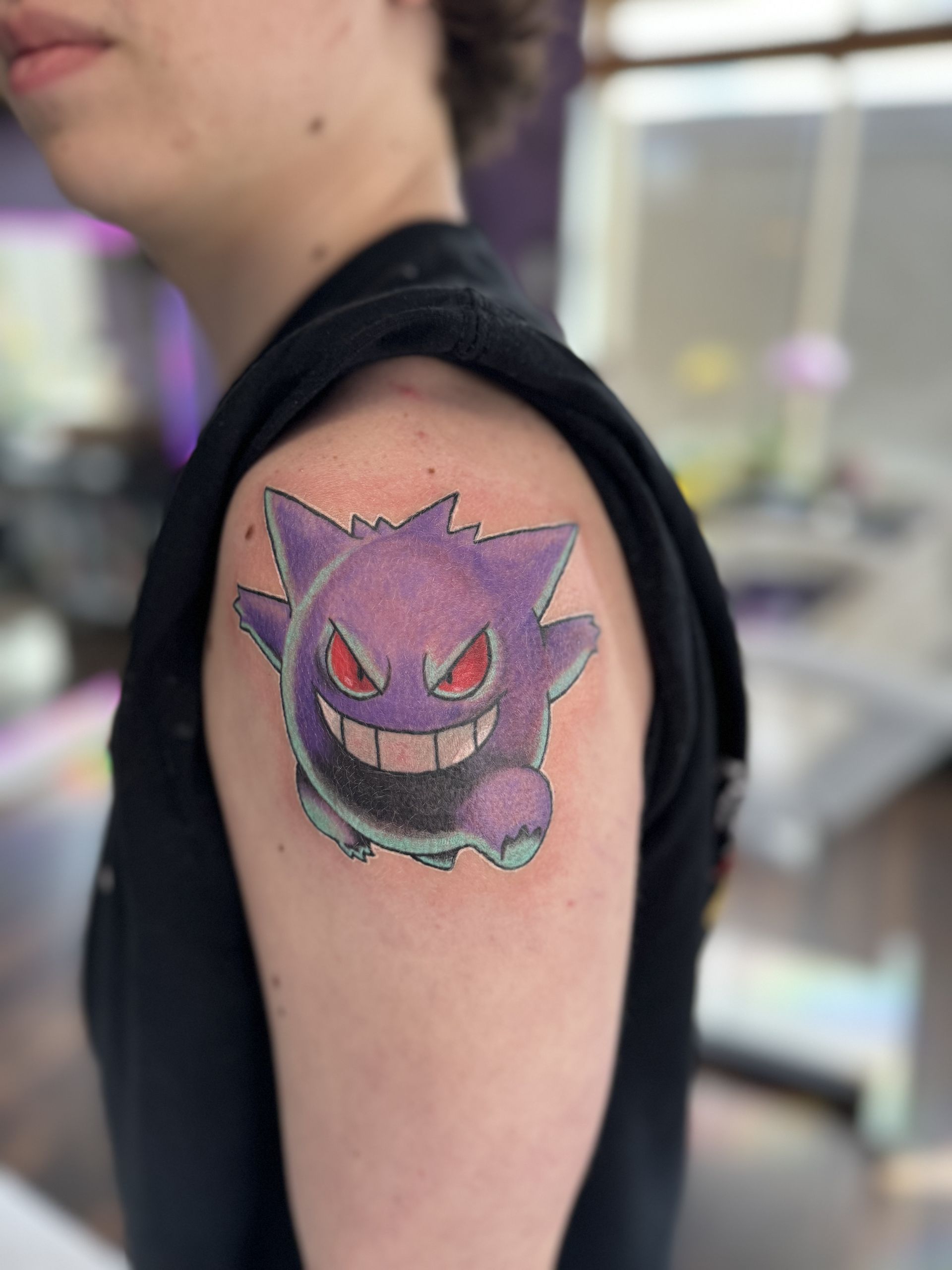 A woman is getting a tattoo on her shoulder.