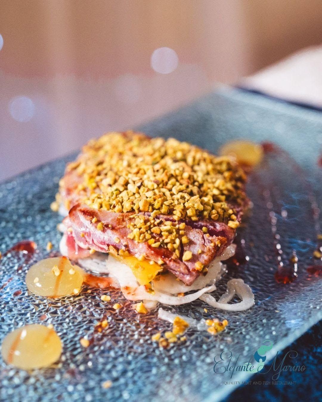 Un trancio di tonno scottato in crosta di pistacchi, servito su un letto di verdure tagliate finemente