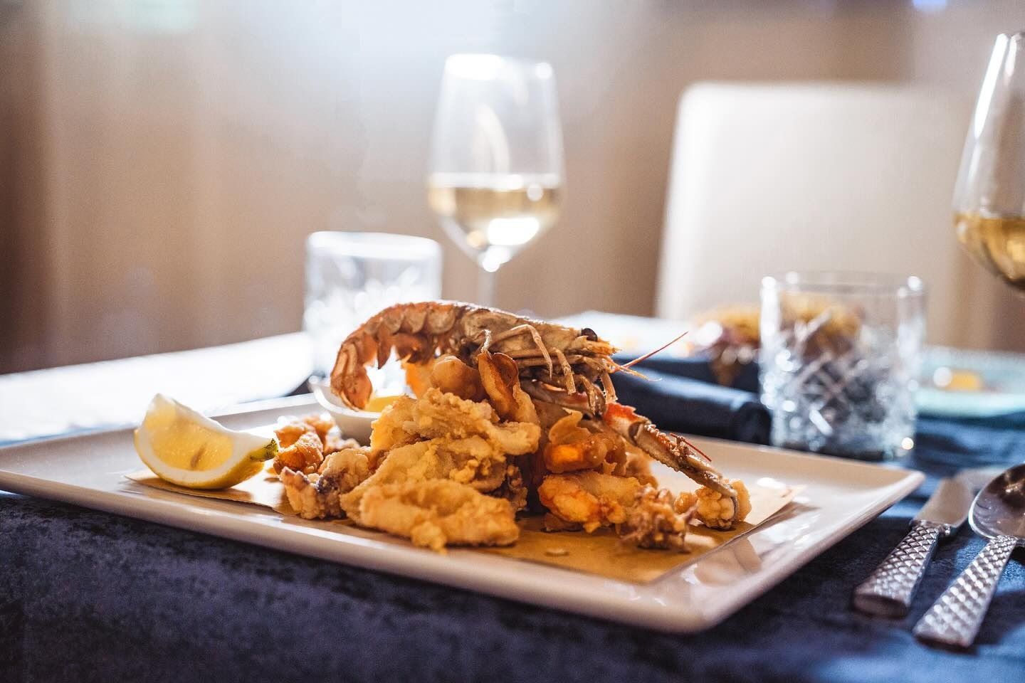 Un piatto di frutti di mare fritti con un crostaceo intero e una fetta di limone su un piatto