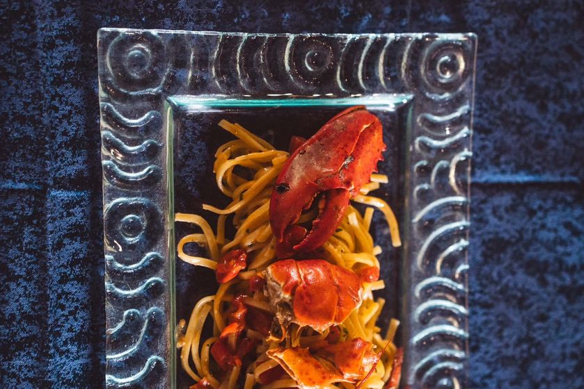 Chef che prepara piatti di mare raffinati, con attenzione alla presentazione e ingredienti freschissimi.