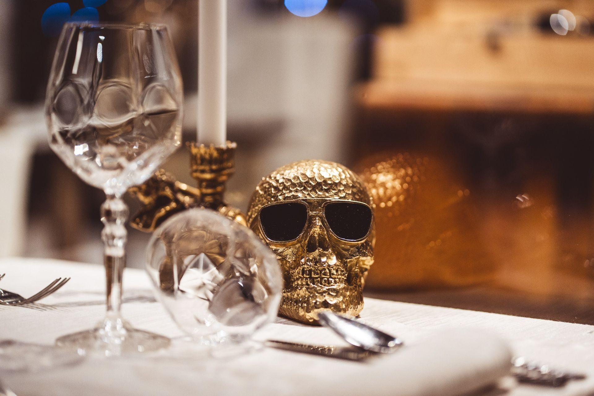 Una tavola apparecchiata presenta un teschio dorato con occhiali da sole