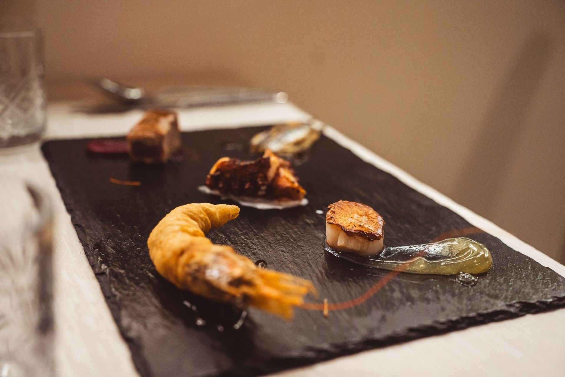 Su un tavolo di ristorante, un piatto di ardesia contiene un gambero impanato