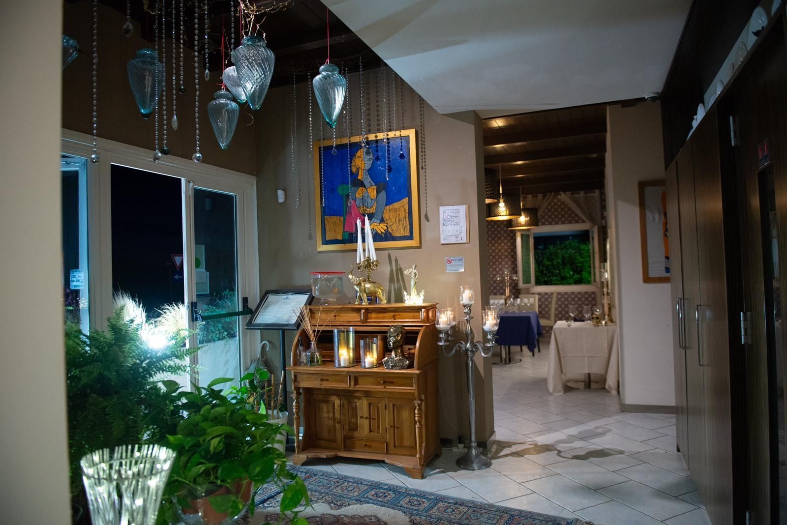 Un ingresso interno illuminato da una luce calda, caratterizzato da una scrivania in legno, un quadro blu