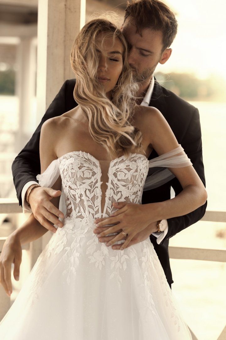 Eine Frau in einem Brautkleid steht vor einem Sonnenuntergang.