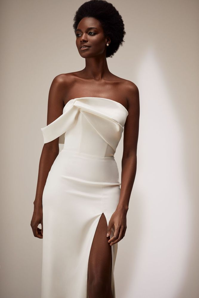 Eine Frau trägt ein weißes trägerloses Kleid mit hohem Schlitz.