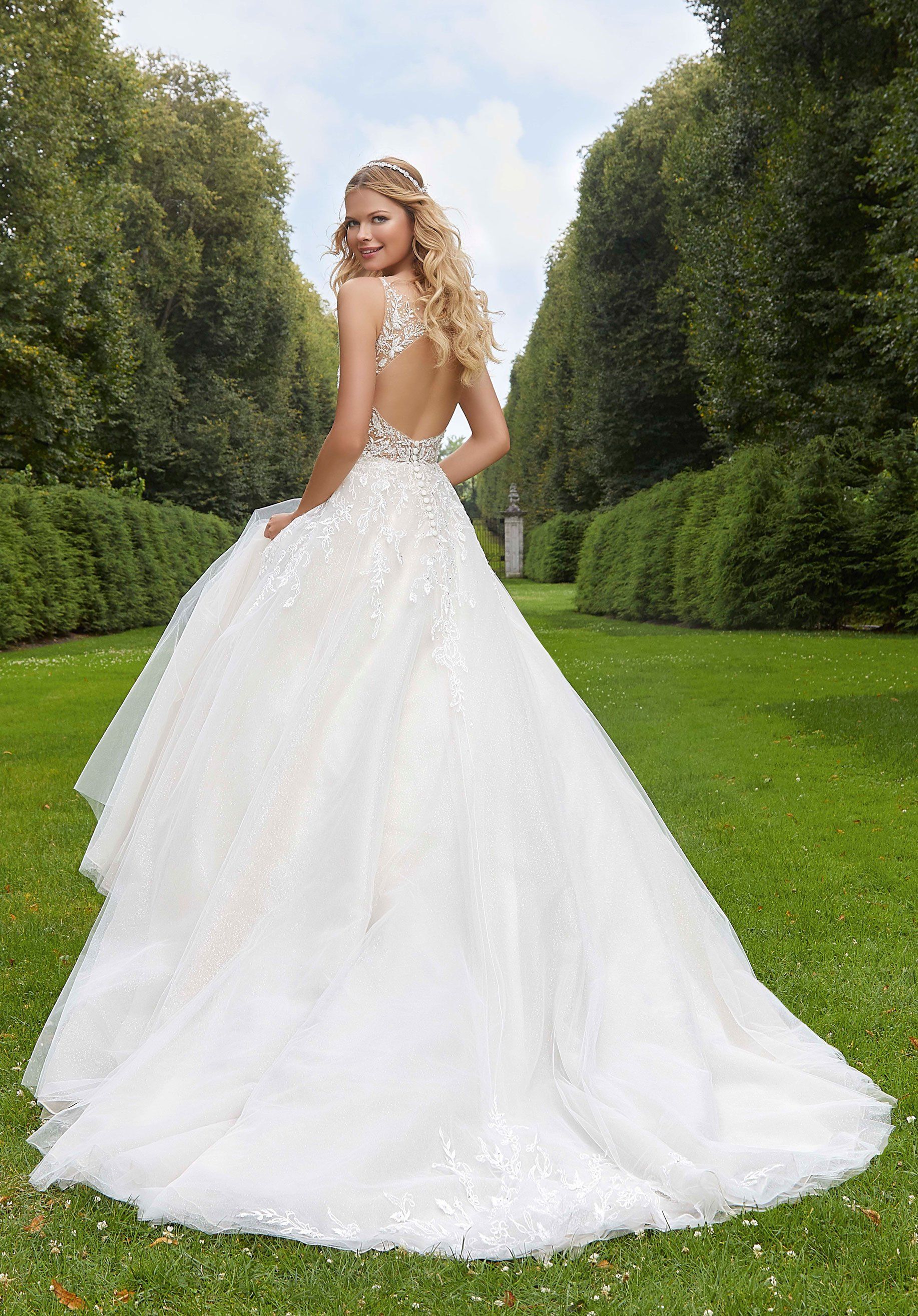 Eine Frau in einem weißen Brautkleid steht im Gras.