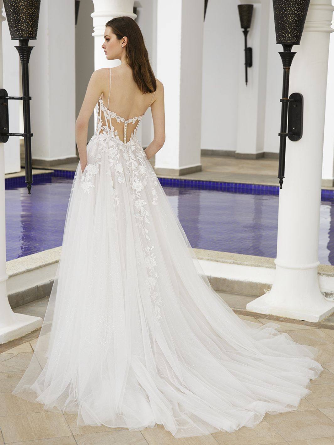 Eine Frau in einem Brautkleid steht vor einem Pool.