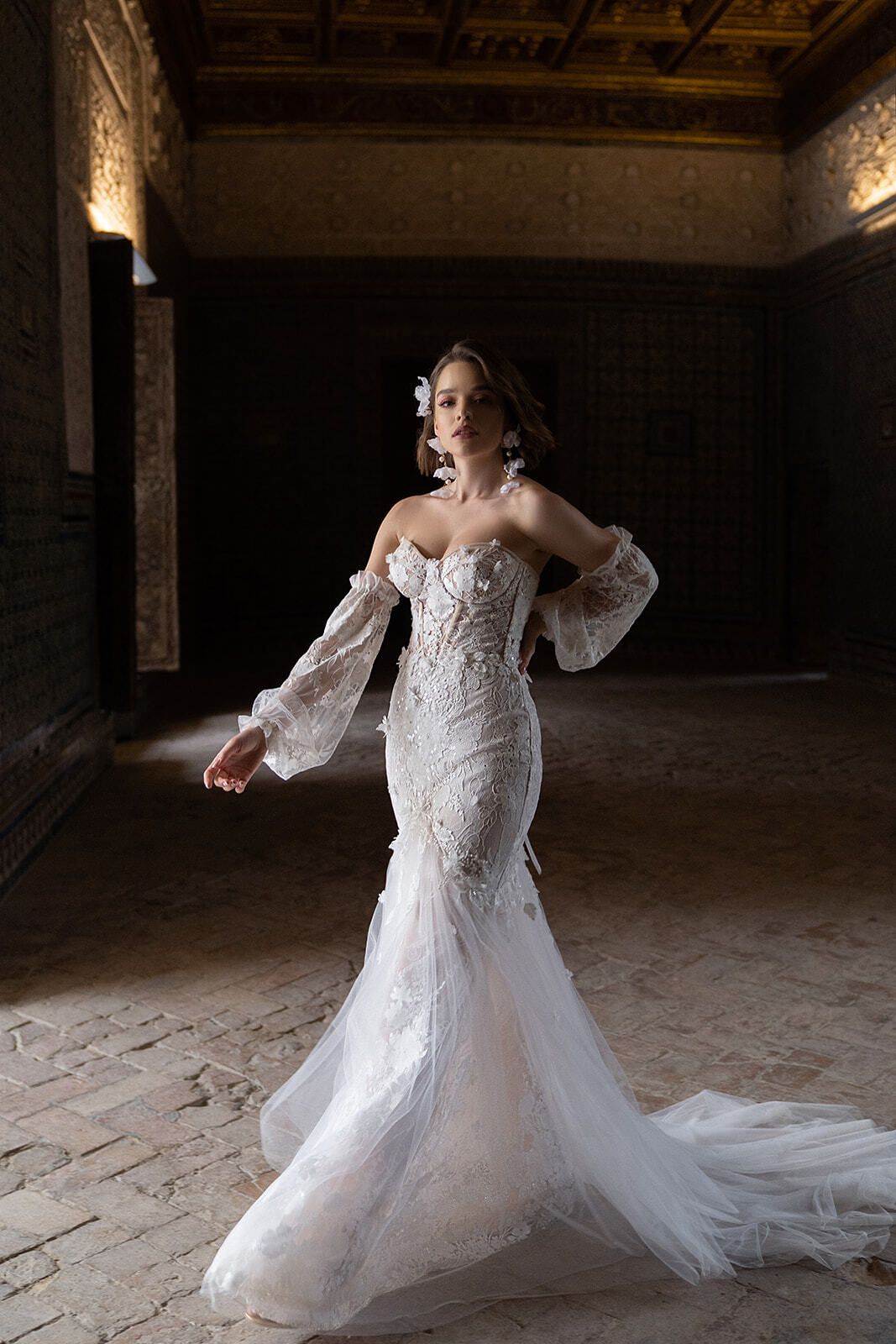 Eine Frau in einem Brautkleid steht in einem dunklen Raum.