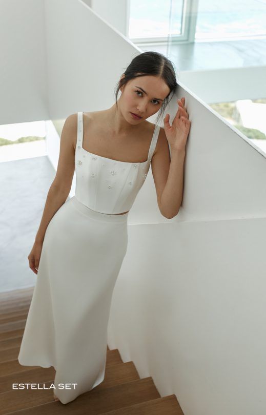 Eine Frau in einem weißen Kleid steht auf einer Treppe.