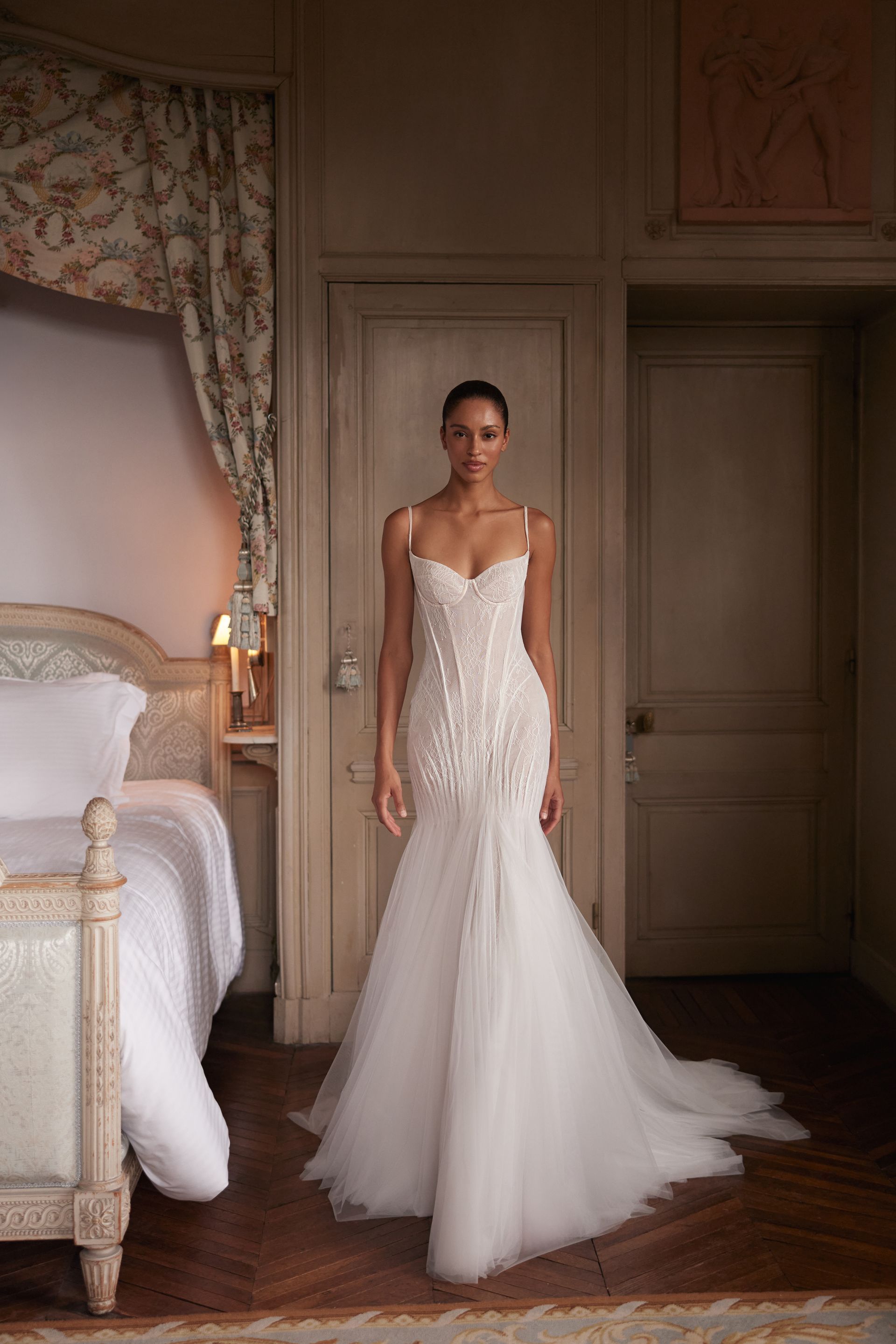 Eine Frau in einem weißen Brautkleid steht vor einem Gewässer.