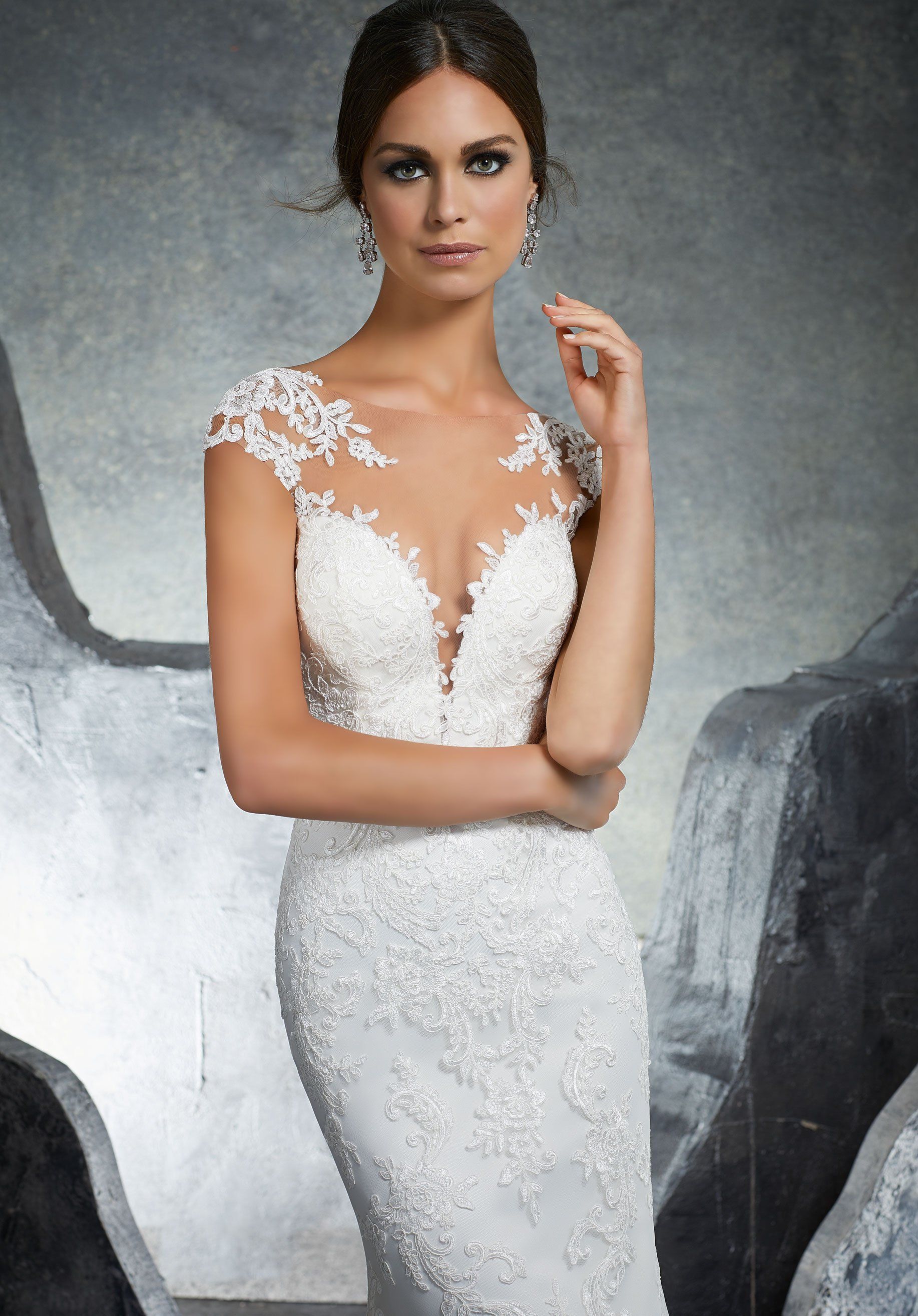 Eine Frau in einem weißen Brautkleid steht vor Felsen.