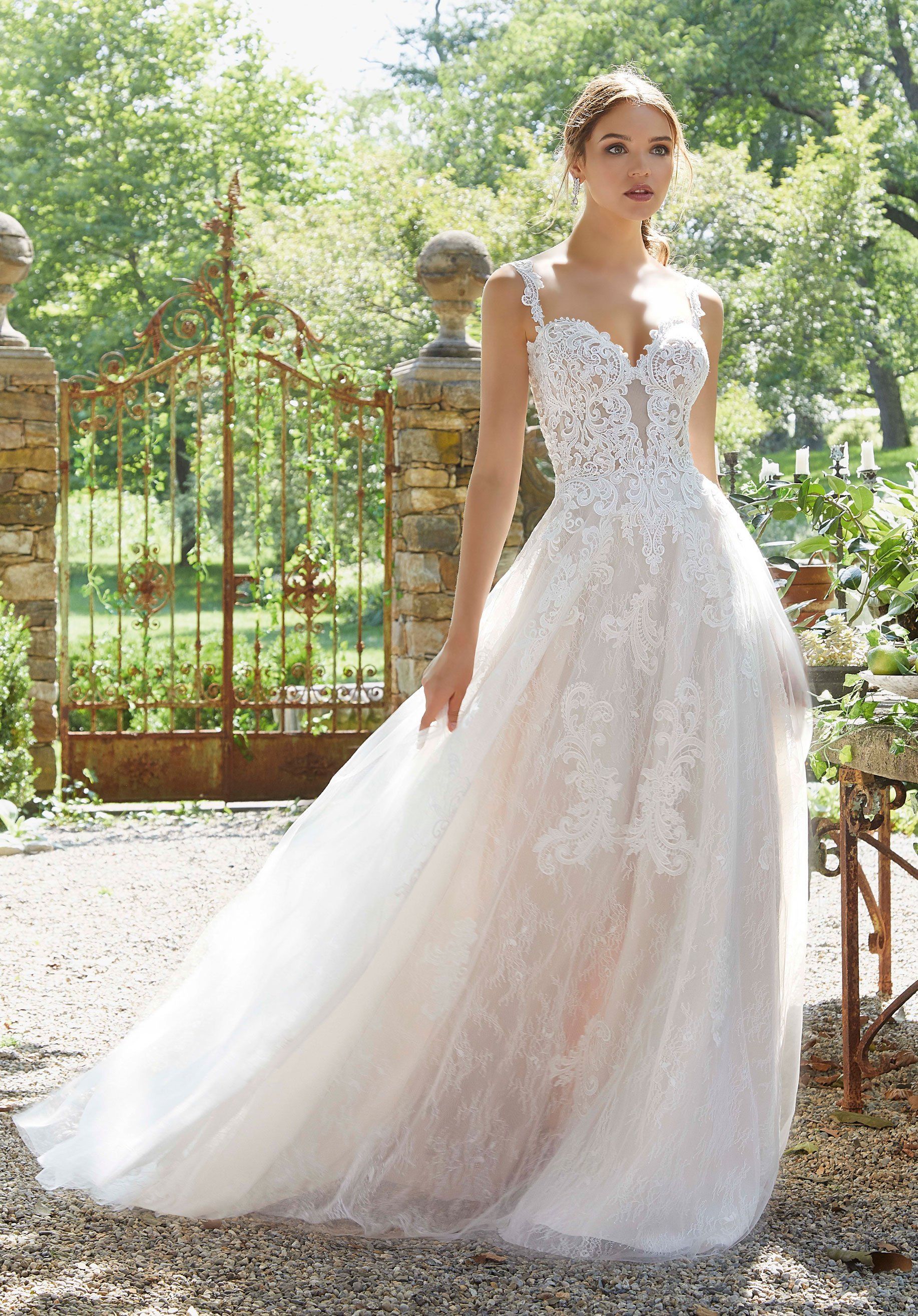 Eine Frau in einem weißen Brautkleid steht vor einem Zaun.