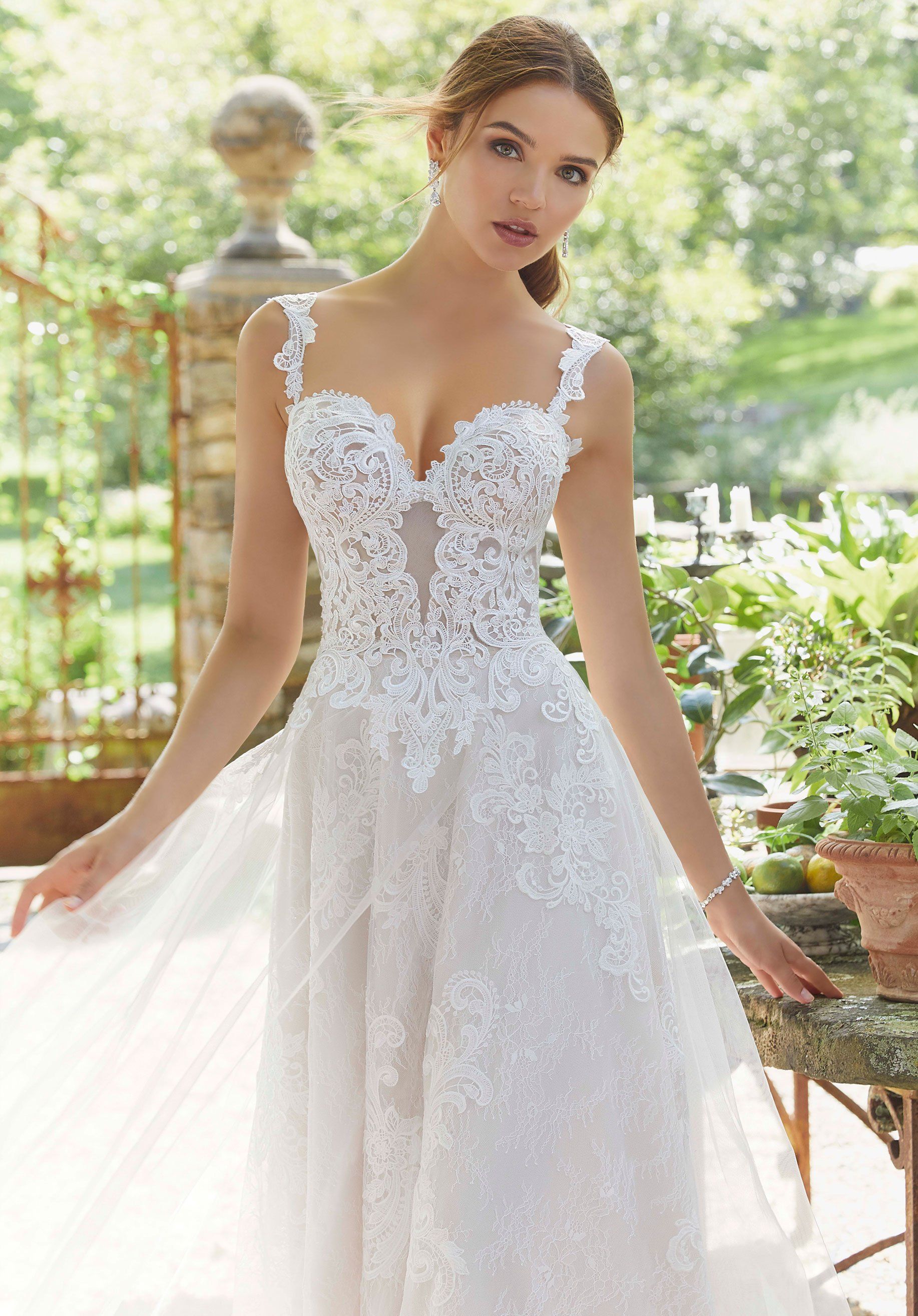 Eine Frau in einem weißen Brautkleid steht in einem Garten.