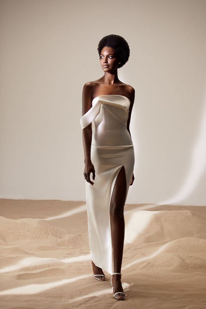 Eine Frau trägt ein weißes trägerloses Kleid mit hohem Schlitz.