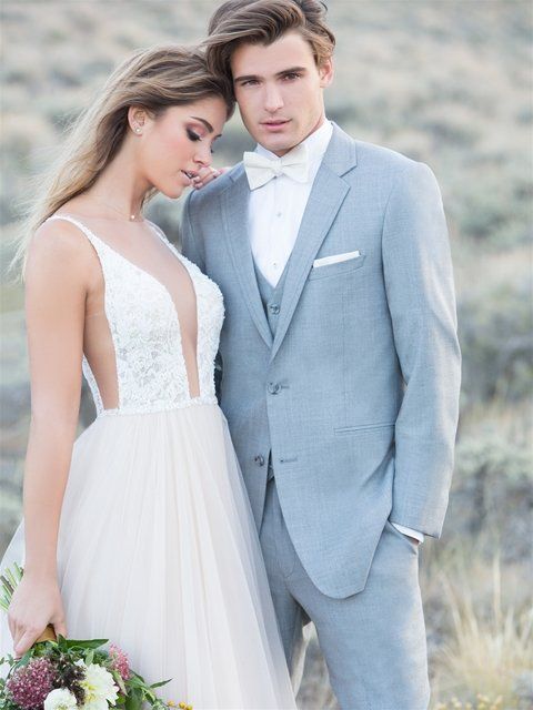 Eine Braut und ein Bräutigam stehen nebeneinander auf einem Feld.