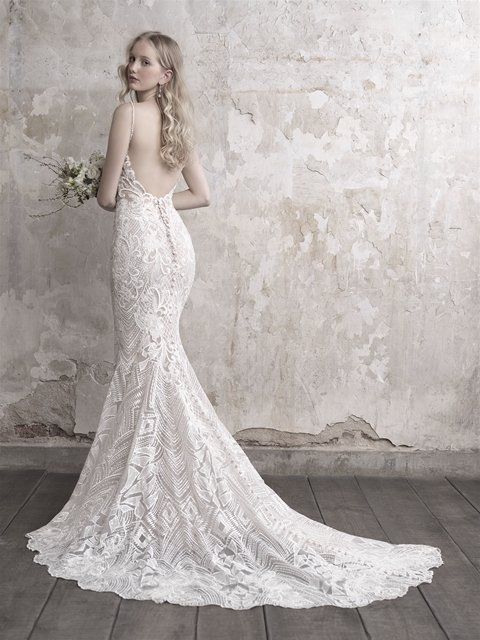 Eine Frau trägt ein weißes Spitzenbrautkleid und hält einen Blumenstrauß in der Hand.