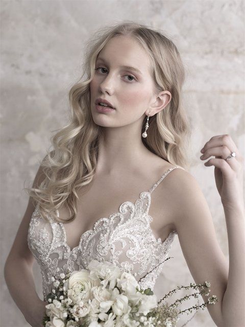 Eine Frau in einem Brautkleid hält einen Strauß weißer Blumen