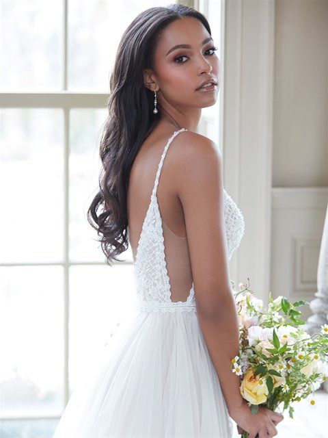 Eine Frau in einem Brautkleid hält einen Blumenstrauß.