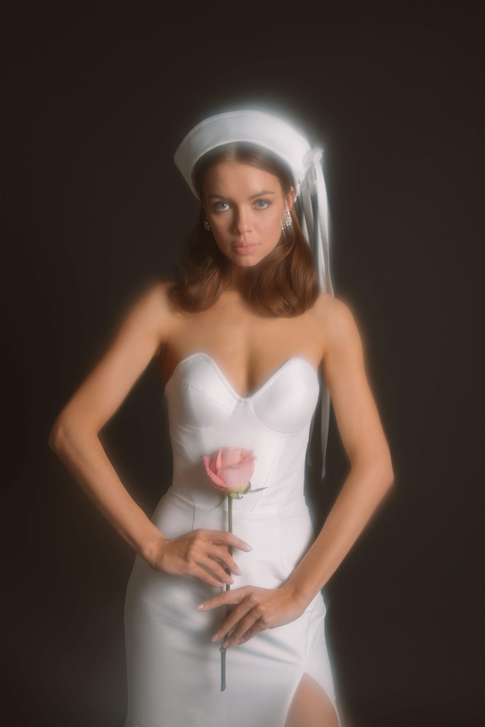 Eine Frau in einem weißen Kleid hält eine rosa Rose.