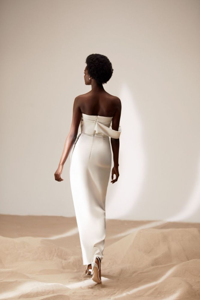 Eine Frau in einem weißen Kleid geht durch die Wüste.