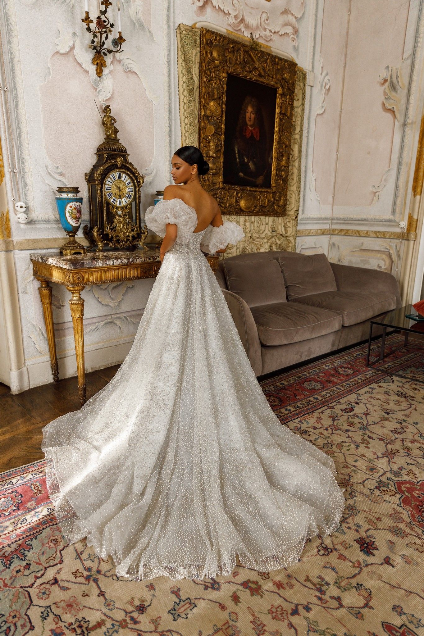 Eine Frau in einem Brautkleid steht in einem Zimmer neben einem Sofa.