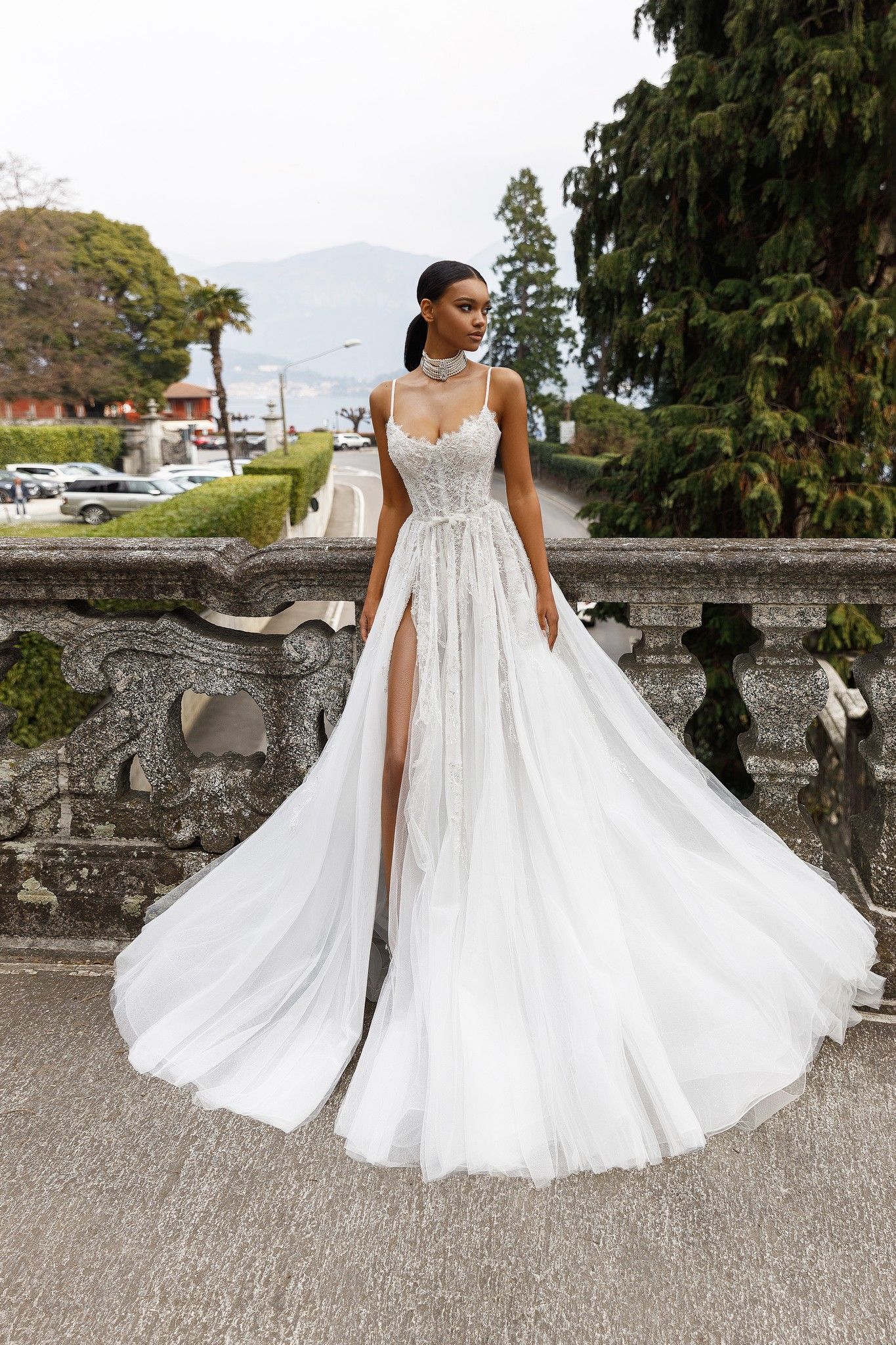 Eine Frau in einem weißen Brautkleid steht neben einer Steinmauer.