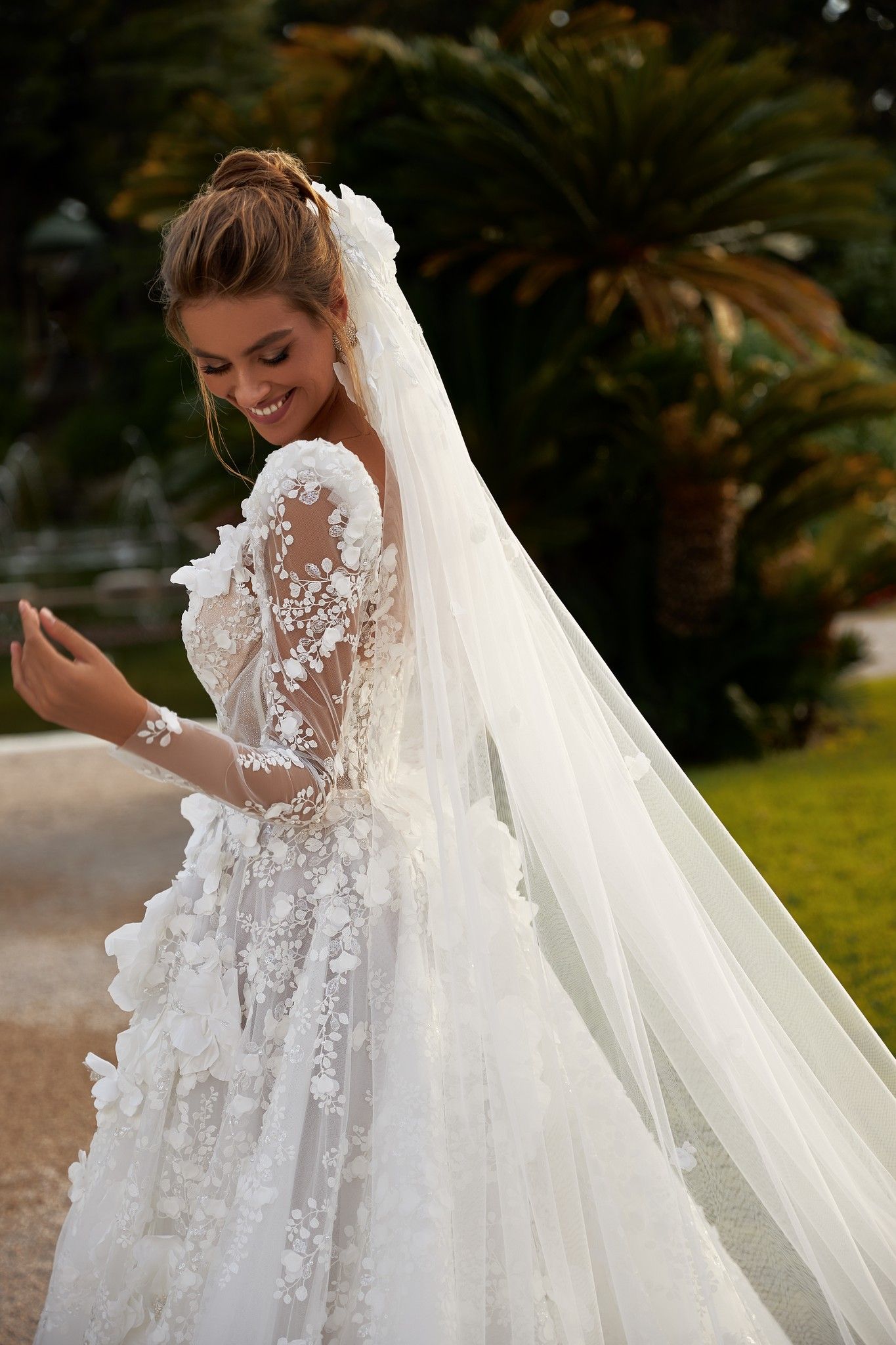Eine Frau in einem Brautkleid und Schleier steht vor einer Palme.